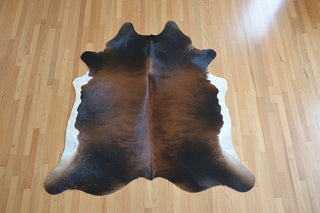 Small dark brindle and white cowhide rug on wood floor